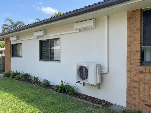 Multi-head split system on a brick-and-render house wall with outdoor unit and pipe covers in Helensvale